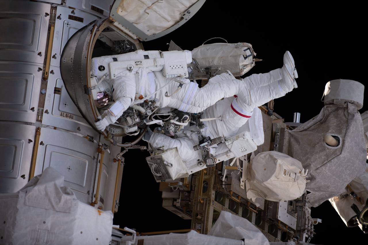 iss069e008039 (April 28, 2023) --- NASA astronaut Stephen Bowen and UAE (United Arab Emirates) astronaut Sultan Alneyadi are pictured in their Extravehicular Mobility Units, or spacesuits, exiting the International Space Station's Quest airlock and beginning a spacewalk. The duo would spend seven hours and one minute in the vacuum of space routing cables and installing insulation readying the orbital outpost for its next set of roll-out solar arrays due to be installed after their delivery on the next SpaceX Dragon cargo mission.