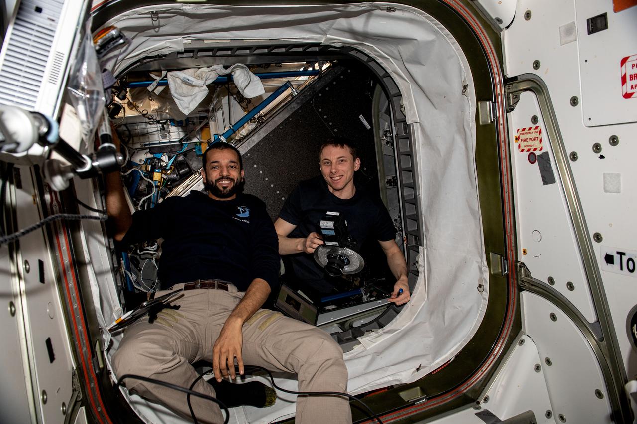 iss069e014400 (May 16, 2023) --- Expedition 69 Flight Engineers (from left) Sultan Alneyadi of UAE (United Arab Emirates) and Woody Hoburg of NASA pose for a portrait inside the vestibule between the Unity module and the Tranquility module during maintenance activities aboard the International Space Station.