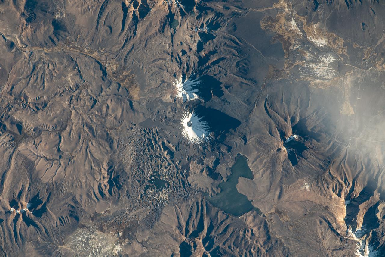 iss069e023100 (June 19, 2023) --- The Pomerape (center top) and Payachata (center bottom) volcanoes and Chungará Lake, on the border between the nations of Chile and Bolivia, are pictured from the International Space Station as it orbited 263 miles above South America.