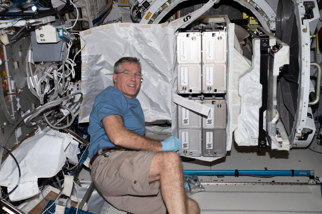 iss069e025742 (June 28, 2023) --- NASA astronaut and Expedition 69 Flight Engineer Stephen Bowen with CubeSats to be deployed from the space station for the 26th NanoRacks CubeSat Deployer (NRCSD-26) mission. The satellites included Nanoracks-RADSAT-SK, which tests a radiation detection system; Nanoracks-SC-ODIN that captures data on dust in storms in Argentina and Namibia; Nanoracks-ESSENCE, to monitor solar storms, arctic ice, permafrost thaw, and forests in the Canadian Arctic region; Nanoracks-Iris, an observation of space weathering of geological samples; and Nanoracks-Ukpik-1, which uses a VR camera to capture 360-degree images and video of Northern Canada.