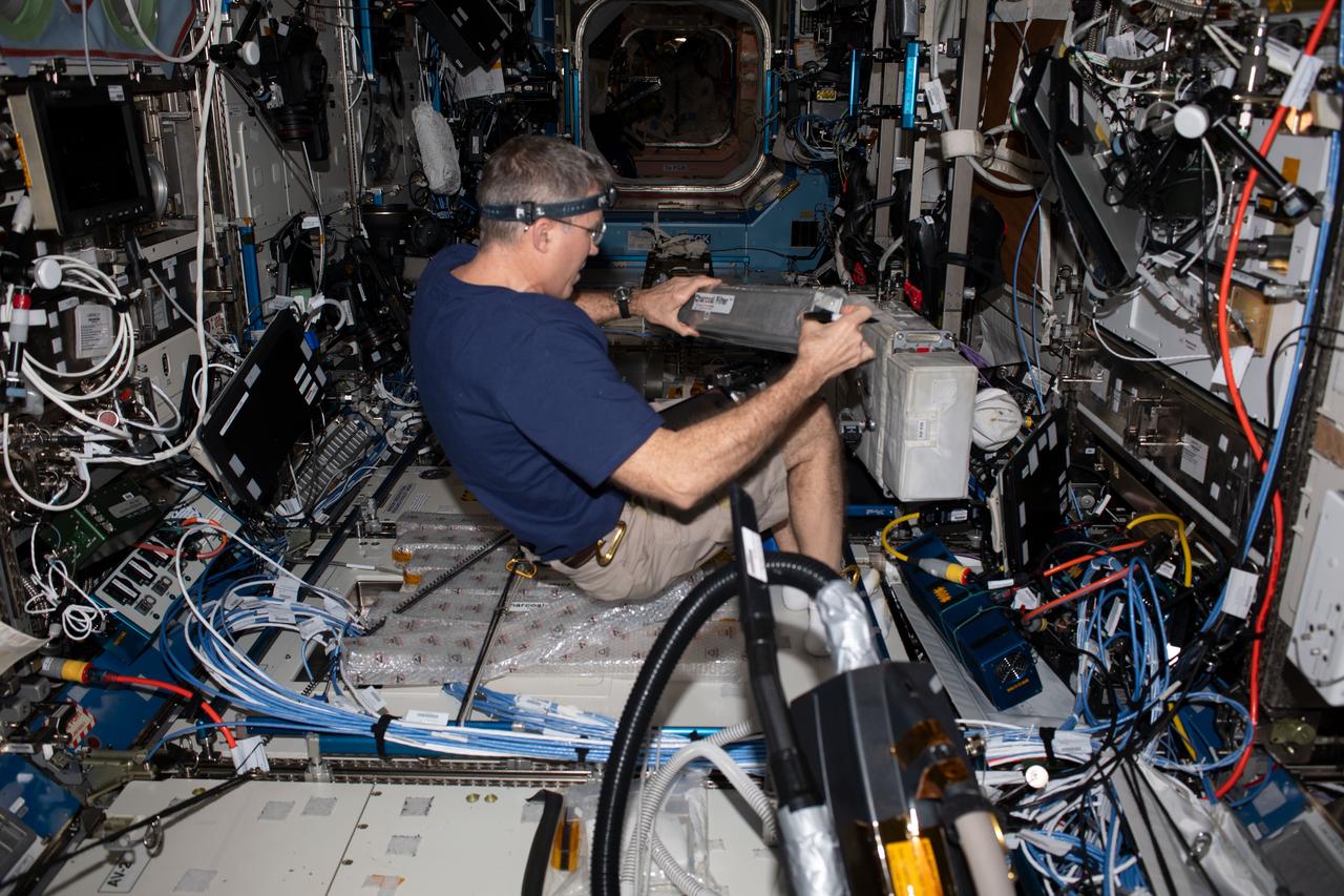 iss069e055090 (Aug. 8, 2023) --- NASA astronaut and Expedition 69 Flight Engineer Stephen Bowen replaces charcoal filters in the Destiny laboratory module as part of life support maintenance aboard the International Space Station.