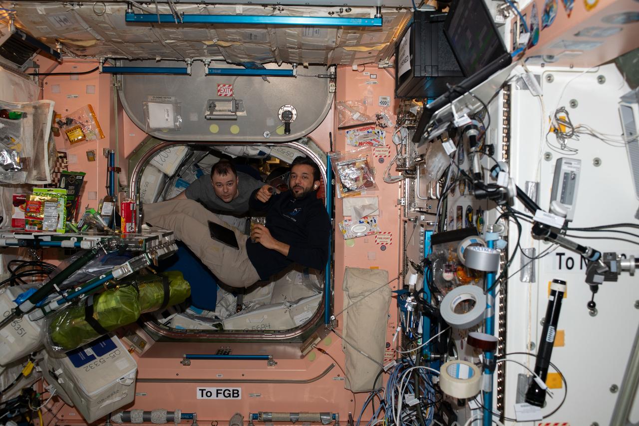 iss069e056754 (Aug. 13, 2023) --- Expedition 69 Flight Engineers (from left) Dmitri Petelin of Roscosmos and Sultan Alneyadi of UAE (United Arab Emirates) are pictured during a snack break inside the International Space Station's  Unity module.