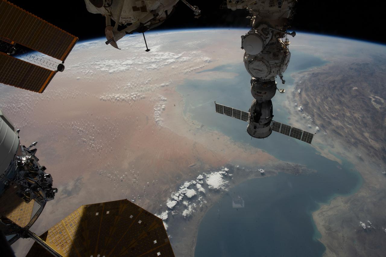 iss069e056939 (Aug. 14, 2023) --- The Strait of Hormuz connects the Gulf of Oman with the Persian Gulf in this photograph from the International Space Station as it orbited 262 miles above. In the right foreground, is the Soyuz MS-23 crew ship docked to the Prichal docking module. At bottom left, is a portion of the Northrop Grumman Cygnus space freighter and one of its cymbal-shaped UltraFlex solar arrays.