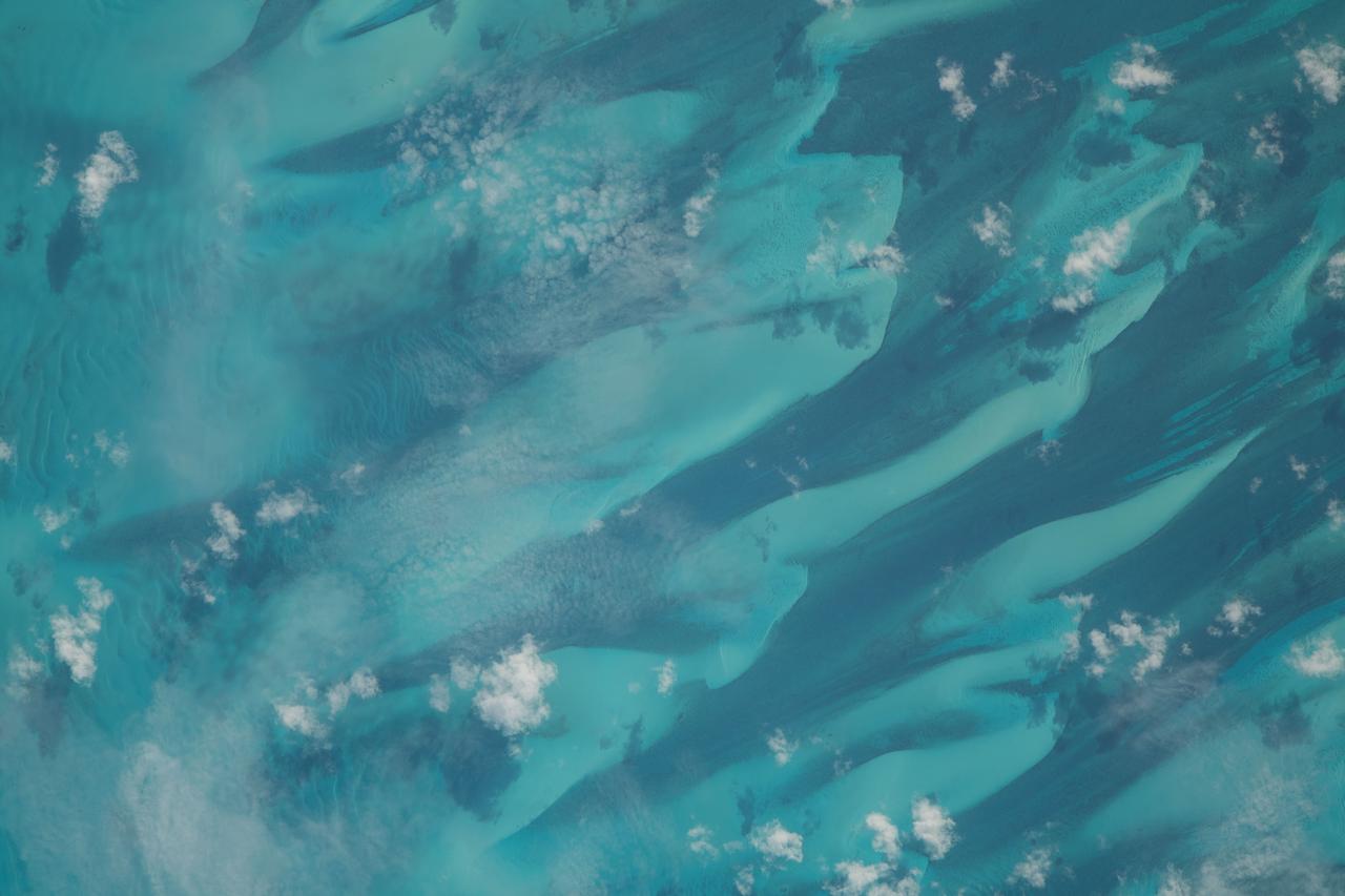 iss069e060929 (August 15, 2023) -- Small scatters of clouds lightly hang over the dark blue and turquoise waters of the Bahamas as the International Space Station soared 262 miles above.
