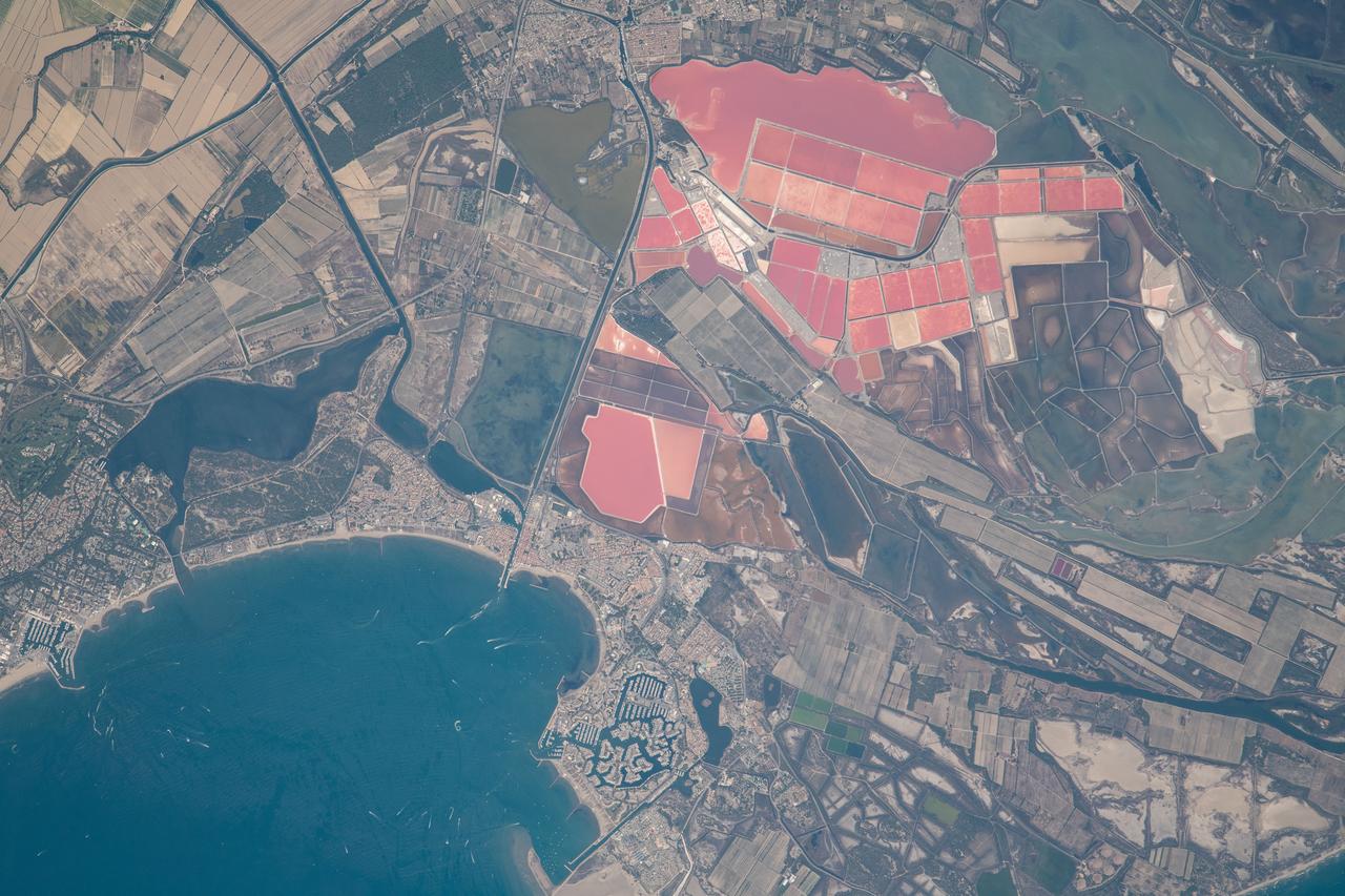 iss069e061413 (August 17, 2023) -- What looks like a collection of fields painted pink is actually a variety of salt lakes in Southern France. Located right off the Mediterranean Sea in the coastal town of Aigues-Mortes, these highly vibrant marshes get their color from pink algae that live within them. The International Space Station was orbiting 265 miles above as this photo was captured.