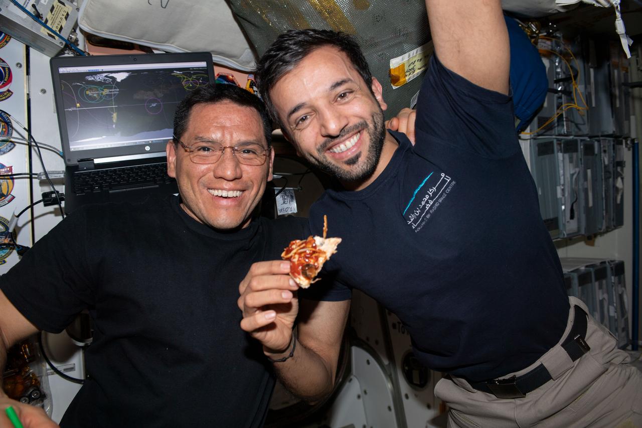 iss069e084178 (Aug. 26, 2023) --- Two Expedition 69 crew members pose for a portrait in the International Space Station's Unity module during the always popular pizza night. From left are, Flight Engineers Frank Rubio from NASA and Sultan Alneyadi from UAE (United Arab Emirates).