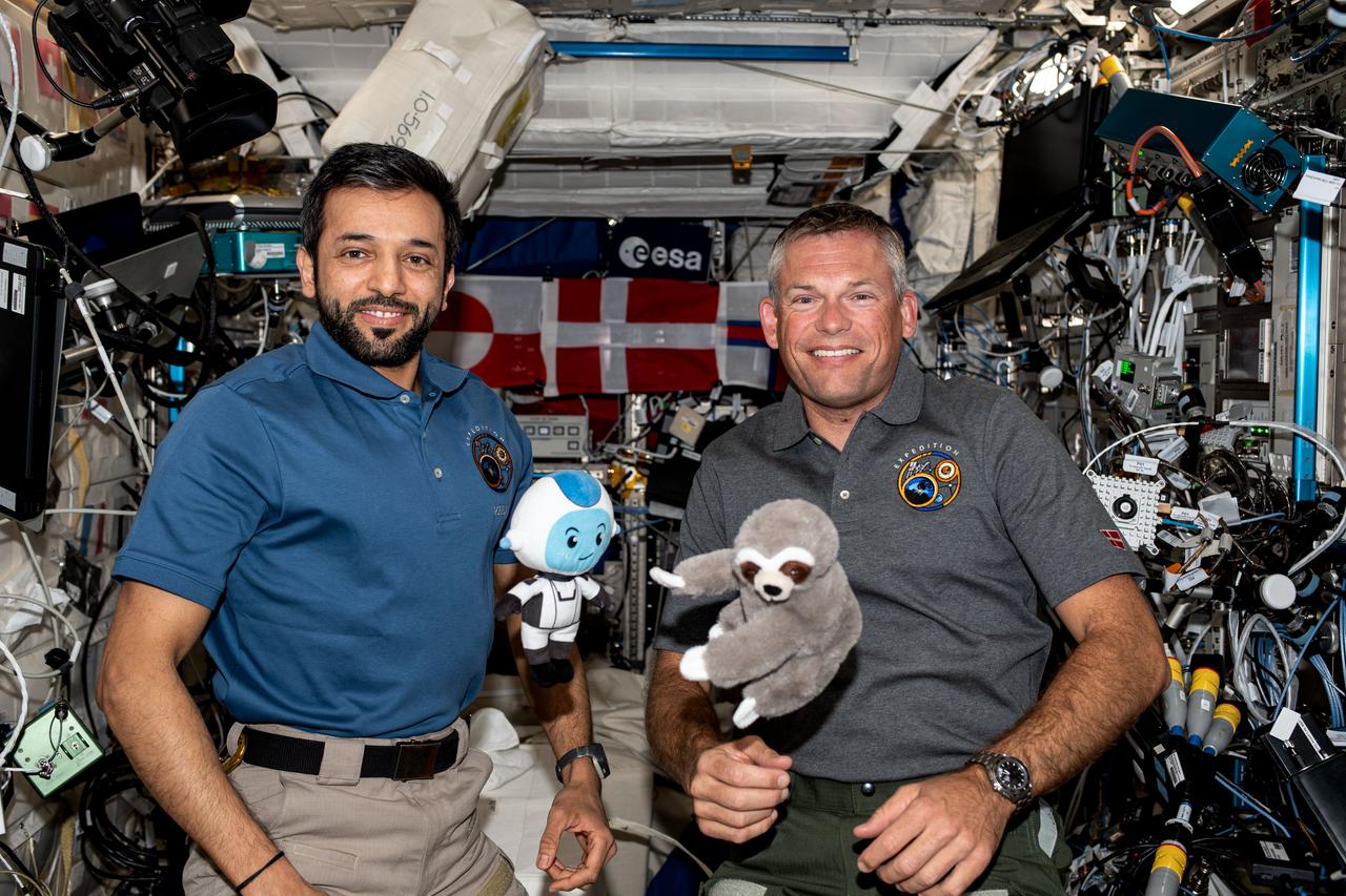 iss069e085315 (Aug. 31, 2023) --- Expedition 69 Flight Engineers Sultan Alneyadi of UAE (United Arab Emirates) and Andreas Mogensen of ESA (European Space Agency) pose for a portrait together aboard the International Space Station's Columbus laboratory module. Alneyadi holds a stuffed doll, Suhail, he carried with him aboard the SpaceX Dragon Endeavour spacecraft. Mogensen shows off a plush three-toed sloth doll he carried aboard the SpaceX Dragon Endurance during his ride to space. The dolls are not just mascots but also gravity indicators to show they have reached space.