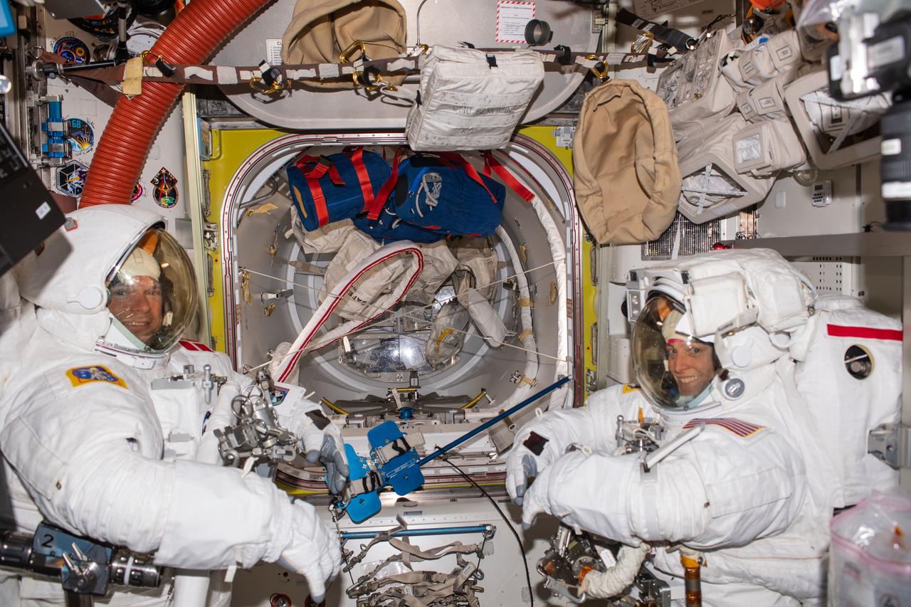 iss070e002035 (Oct. 4, 2023) --- (From left) Astronauts Andreas Mogensen from ESA (European Space Agency) and Loral O'Hara from NASA try on their spacesuits and test the suits' components aboard the International Space Station's Quest airlock in preparation for an upcoming spacewalk.