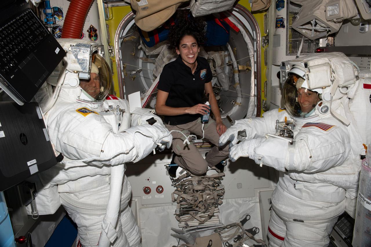 iss070e002430 (Oct. 4, 2023) --- NASA astronaut Jasmin Moghbeli (center) assists astronauts Andreas Mogensen (left) from ESA (European Space Agency) and Loral O'Hara (right) from NASA as they try on their spacesuits and test the suits' components aboard the International Space Station's Quest airlock in preparation for an upcoming spacewalk.