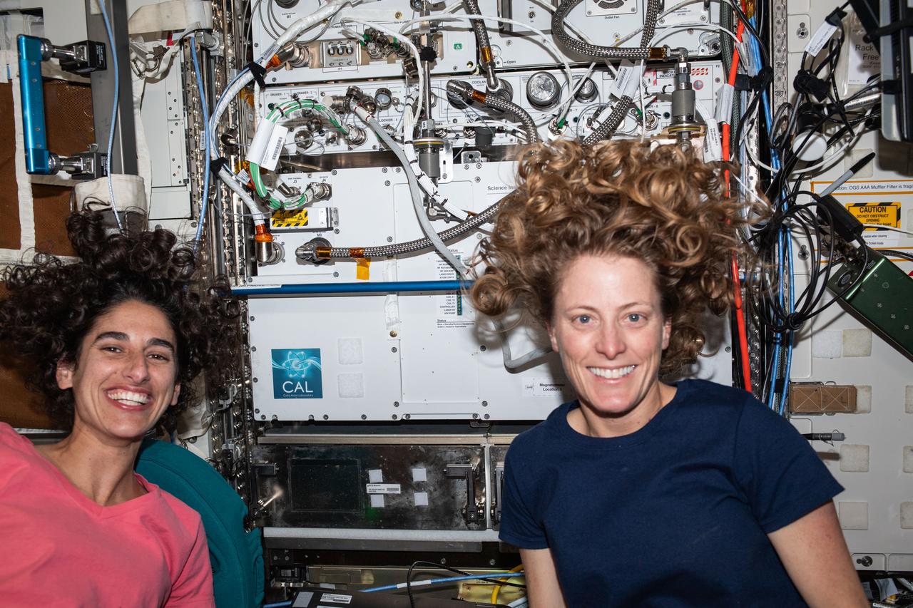iss070e003191 (Oct. 12, 2023) --- Expedition 70 Flight Engineers (from left) Jasmin Moghbeli and Loral O'Hara, both from NASA, pose for a portrait in front of the International Space Station's Cold Atom Lab. The physics research device observes the quantum behavior of atoms chilled to about one ten billionth of a degree above absolute zero -- much colder than the average temperature of deep space.