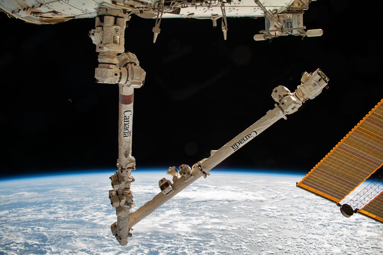 iss070e006089 (Oct. 18, 2023) --- The Canadarm2 robotic arm is pictured extending from the International Space Station while orbiting 260 miles above the Pacific Ocean near the Aleutian Islands.