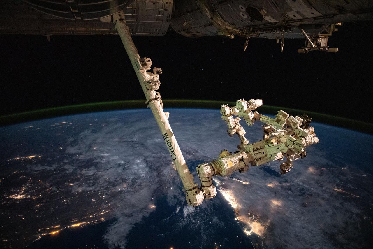 iss070e014288 (Oct. 26, 2023) --- The Canadarm2 robotic arm, with its fine-tuned robotic hand Dextre attached, is pictured as the International Space Station orbited 260 miles above the city lights of the Arabian Peninsula.