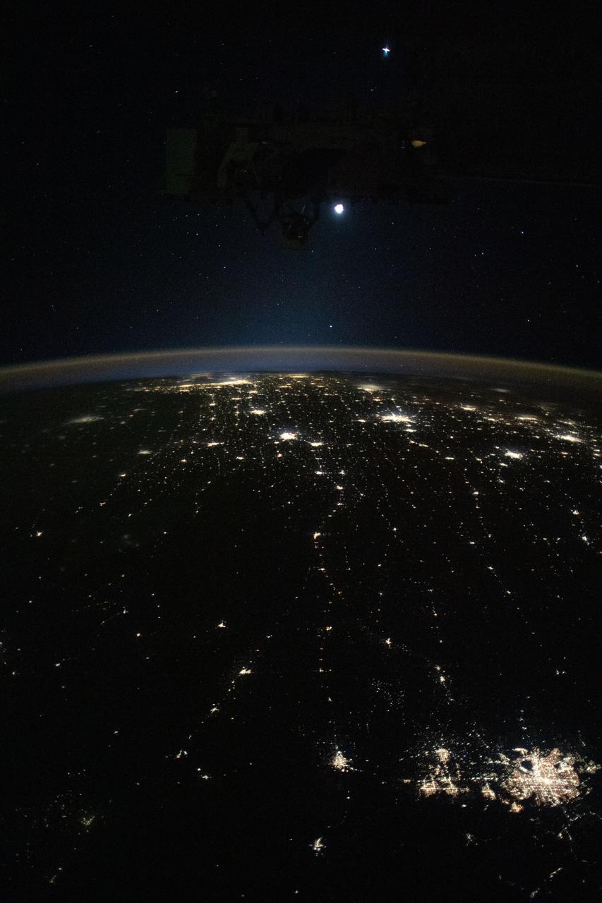 iss070e022666 (Nov. 10, 2023) --- Earth's airglow outlines the planet's horizon with the Moon above in this photograph from the International Space Station as it orbited 260 miles above the midwestern United States. At lower right, the city lights of Denver. Colorado, and its suburbs shine, including the city lights all the way to Chicago, Illinois (at top), and surrounding metropolitan areas.