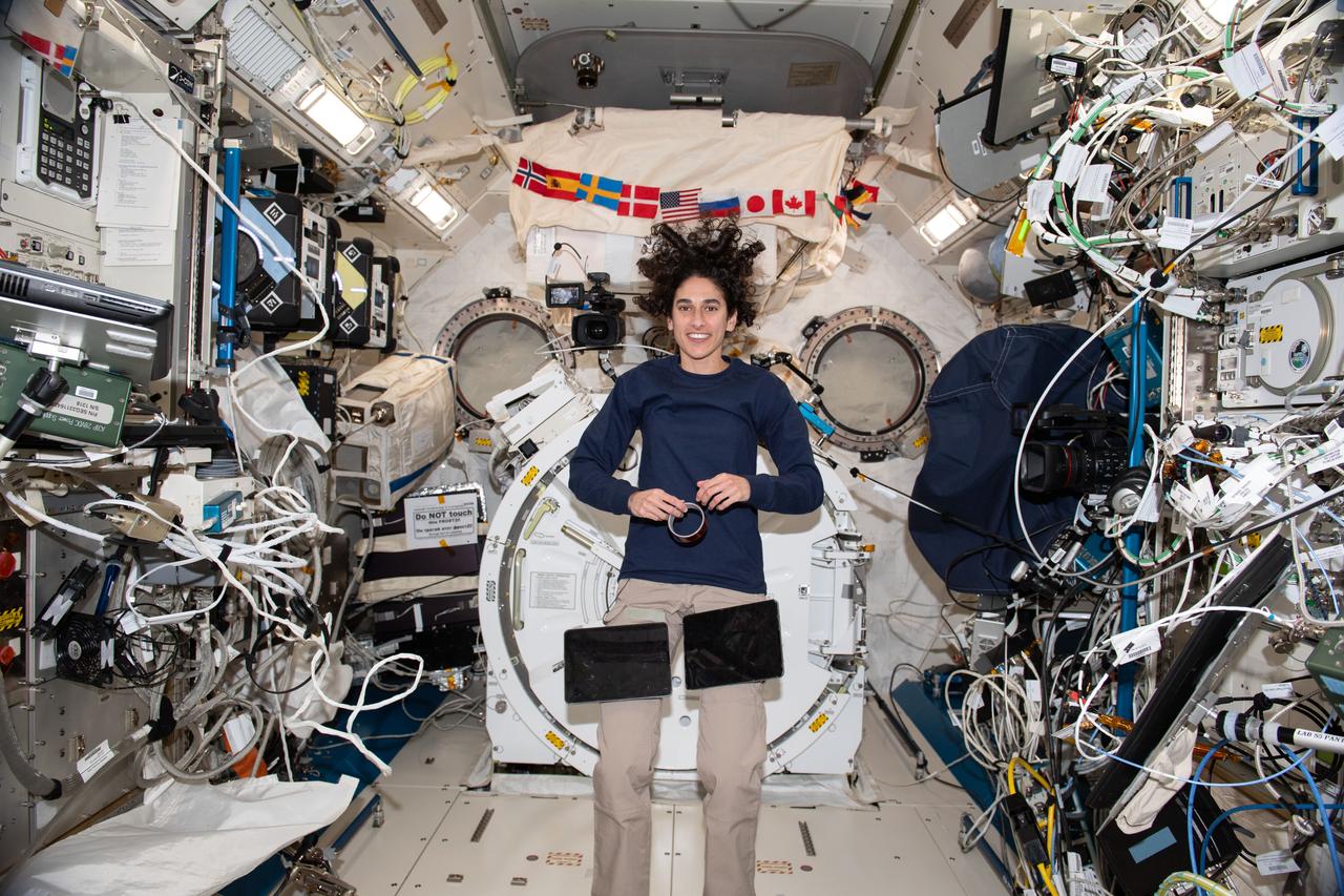 iss070e035105 (Nov. 30, 2023) --- NASA astronaut and Expedition 70 Flight Engineer Jasmin Moghbeli takes a break during operations and poses for a portrait inside the International Space Station's Kibo laboratory module. A pair of computer tablets are attached to velcro straps on Moghbeli's pants for ease of access when reviewing procedures and instructions.