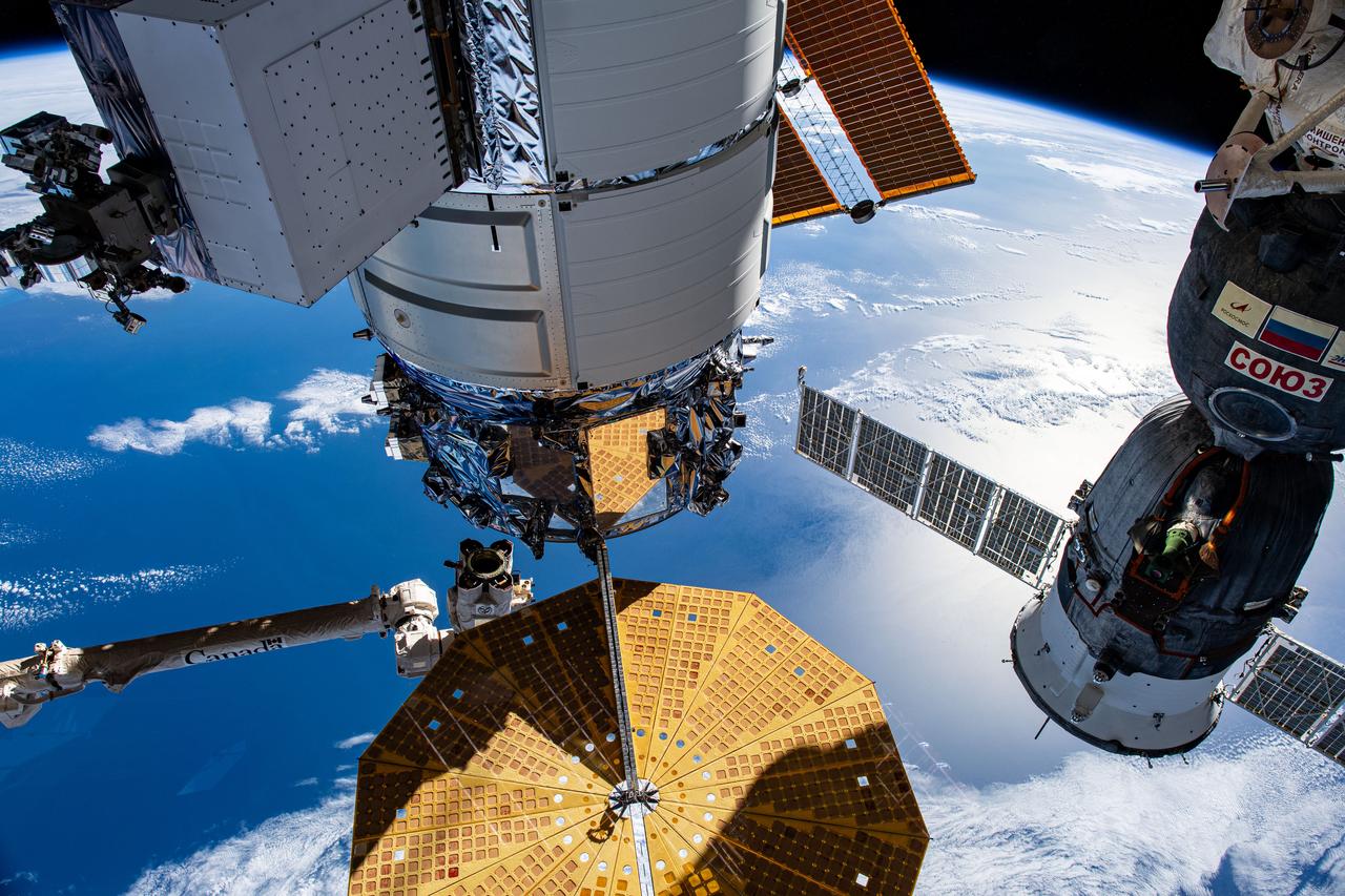 iss070e043731 (Dec. 20, 2023) --- Northrop Grumman's Cygnus space freighter and the Roscosmos Soyuz MS-24 crew ship (at right) are pictured attached to the International Space Station while orbiting 266 miles above the Indian Ocean south of the island nation of Madagascar. At lower left, is the Canadarm2 robotic arm preparing to grapple Cygnus ahead of its removal from the Unity module and departure from the orbital outpost.