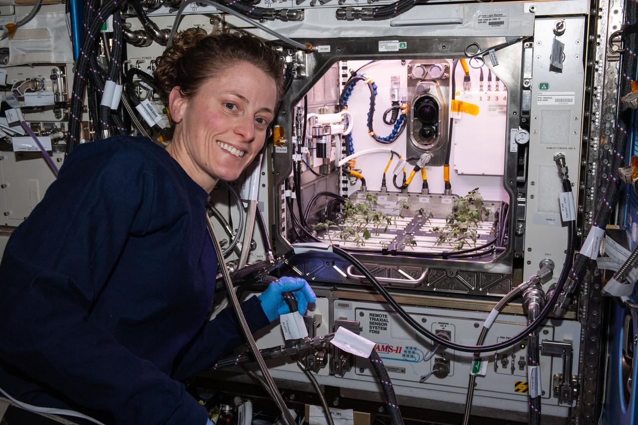 iss070e073610 (Jan. 18, 2024) --- NASA astronaut and Expedition 70 Flight Engineer Loral O'Hara poses in front of the Kibo laboratory module's Advanced Plant Habitat housing tomato plants for an experiment investigating how the plant immune system adapts to spaceflight and how spaceflight affects plant production.