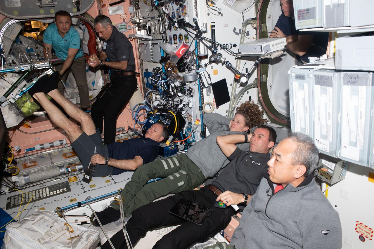 iss070e083375 (Jan. 27, 2024) --- Members of the Axiom Mission 3 (Ax-3) and Expedition 70 crews join each other for movie night inside the International Space Station's Harmony module. From left are, Ax-3 Mission Specialist Alper Gezeravcı; Ax-3 Pilot Walter Villadei; Ax-3 Commander Michael López-Alegría; Expedition 70 Flight Engineer Loral O'Hara from NASA; Ax-3 Mission Specialist Marcus Wandt; and Expedition 70 Flight Engineer Satoshi Furukawa from JAXA (Japan Aerospace Exploration Agency); partially obscured at top right is, Expedition 70 Commander Andreas Mogensen from ESA (European Space Agency).