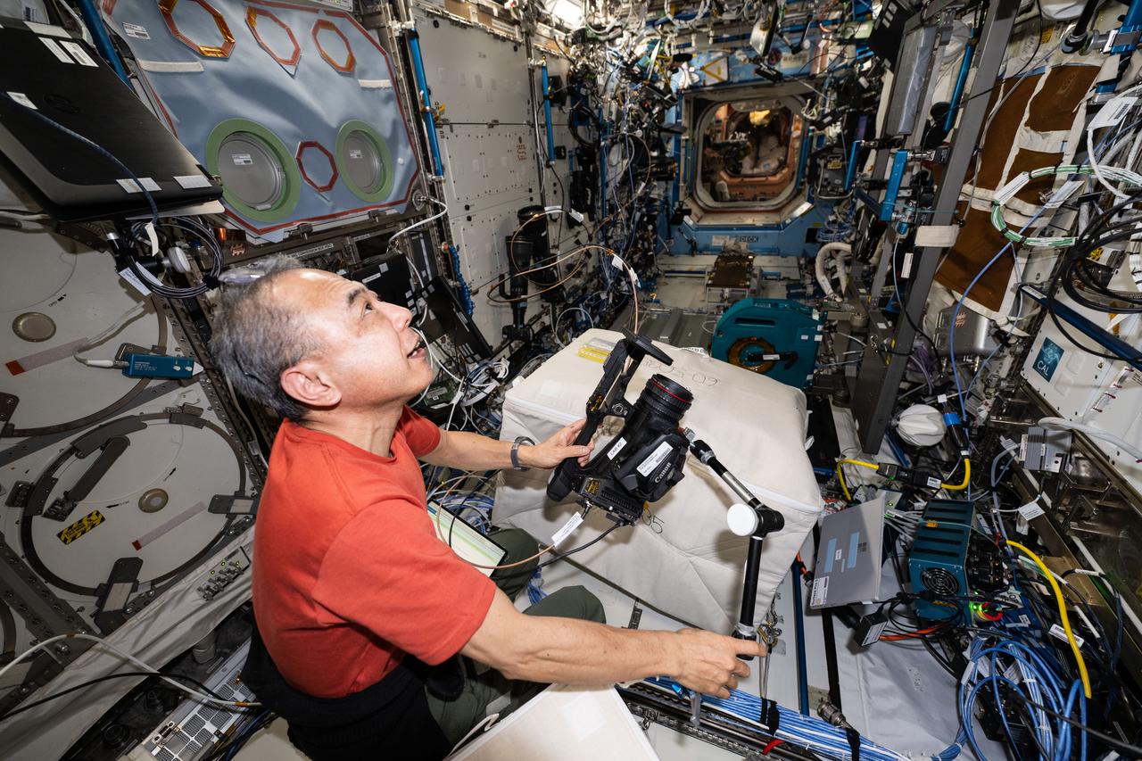 iss070e108767 (March 6, 2024) --- Expedition 70 Flight Engineer and JAXA (Japan Aerospace Exploration Agency) astronaut Satoshi Furukawa sets up a video camera that will record him working on a physics experiment inside the International Space Station's Destiny laboratory module.