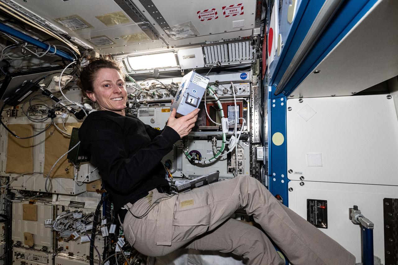 iss070e129524 (March 25, 2024) --- Expedition 70 Flight Engineer and NASA astronaut Loral O'Hara shows off the Advanced Space Experiment Processor-2, or ADSEP-2. The scientific device can interface with the Dragon and Cygnus cargo craft and houses cassettes that process samples for biology and physics research including cell and tissue culturing, protein crystal growth, microorganism and bacteria studies, and materials science research.