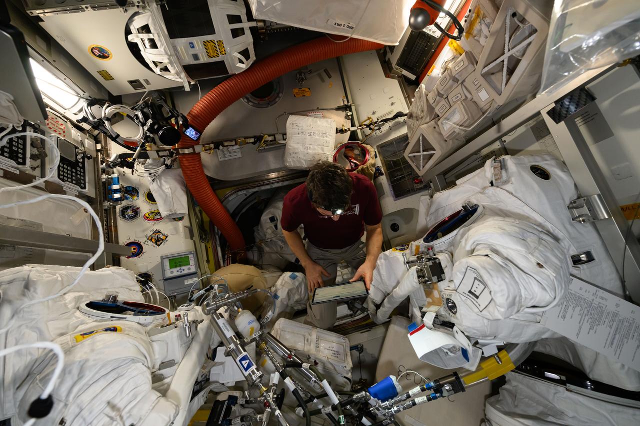 iss071e007603 (April 15, 2024) --- Expedition 71 Flight Engineer and NASA astronaut Mike Barratt reviews procedures on a computer tablet during maintenance on a pair of spacesuits inside the International Space Station's Quiest airlock.