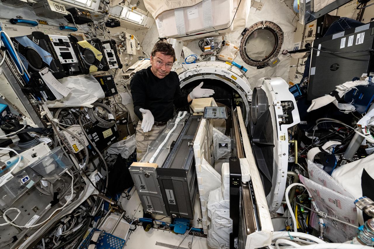iss071e008781 (April 16, 2024) --- Expedition 71 Flight Engineer and NASA astronaut MIke Barratt poses for a portrait while installing a small satellite orbital deployer inside the Kibo laboratory module's airlock. The Japanese robotic arm will grapple the deployer and point it away from the station where it will release a series of CubeSats into Earth orbit for scientific and technology research.