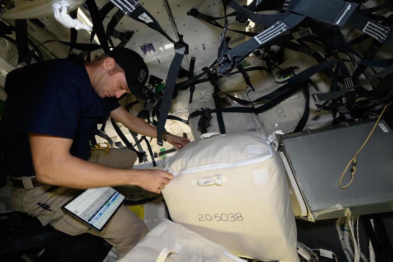 iss071e013805 (April 22, 2024) --- Expedition 71 Flight Engineer and NASA astronaut Matthew Dominick checks procedures on a computer tablet while loading cargo for return to Earth inside the SpaceX Dragon spacecraft.
