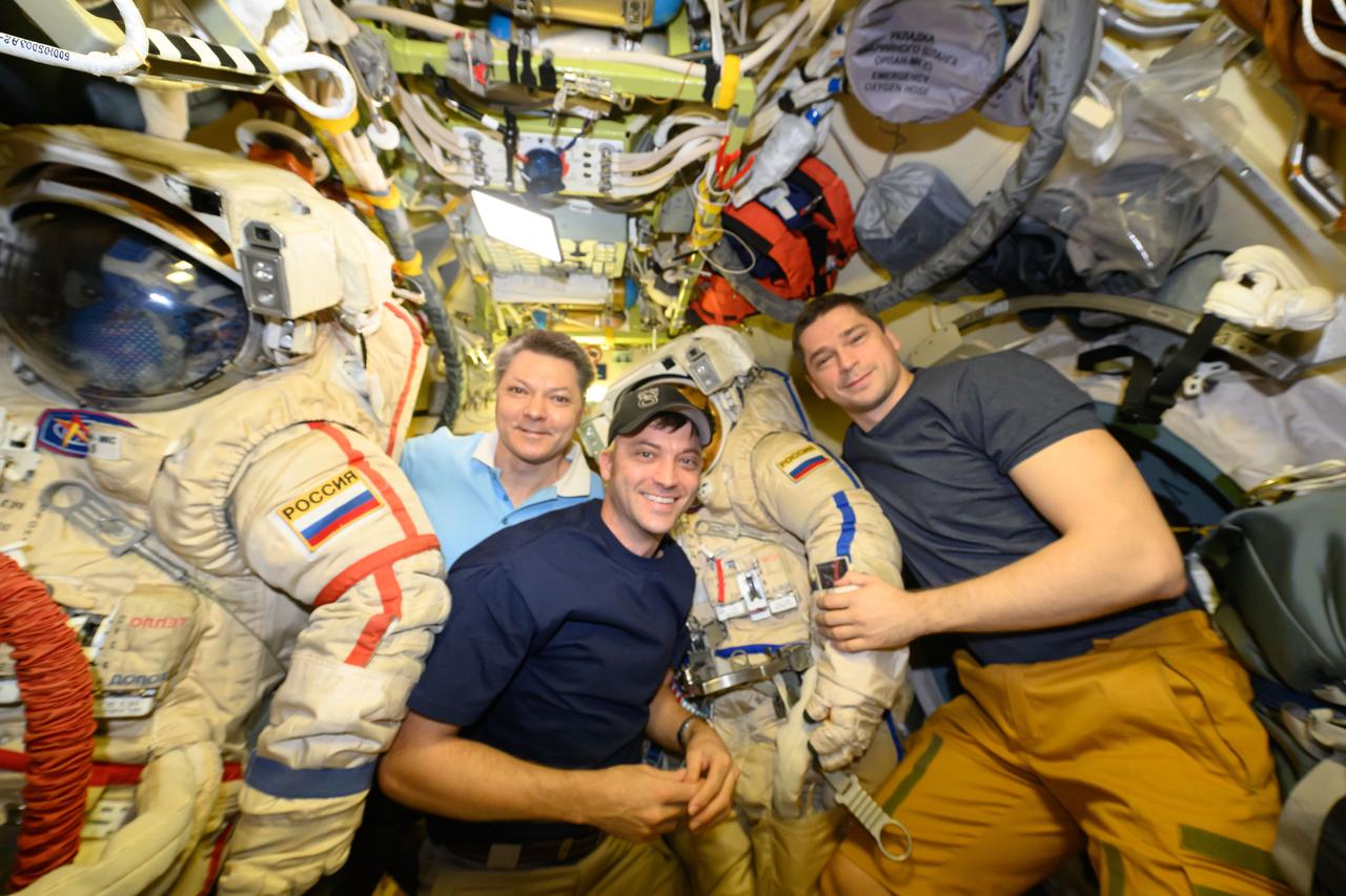 iss071e013949 (April 20, 2024) --- NASA astronaut Matthew Dominick (center) poses for a portrait with Expedition 71 Commander Oleg Kononenko (left) and Flight Engineer Nikolai Chub, both Roscosmos cosmonauts. Dominick was inside the Poisk module assisting Kononenko and Chub as they prepared their Orlan spacesuits for a spacewalk to configure hardware and install experiments on the International Space Station.