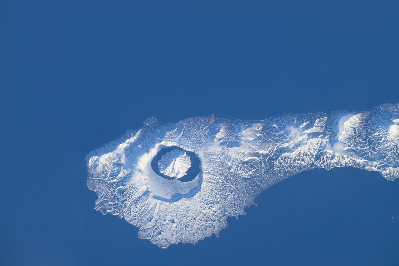 iss071e046424 (April 29, 2024) --- The snow-covered Onekotan Island, part of Russia's Kuril Islands, is home to the Tao-Rusyr Caldera stratovolcano in this photograph. Inside the caldera is the Krenitsyna Volcano peak surrounded by the partially ice-covered Kol'tsevoe Lake. The International Space Station was orbiting 259 miles above the Pacific Ocean at the time of this photograph.