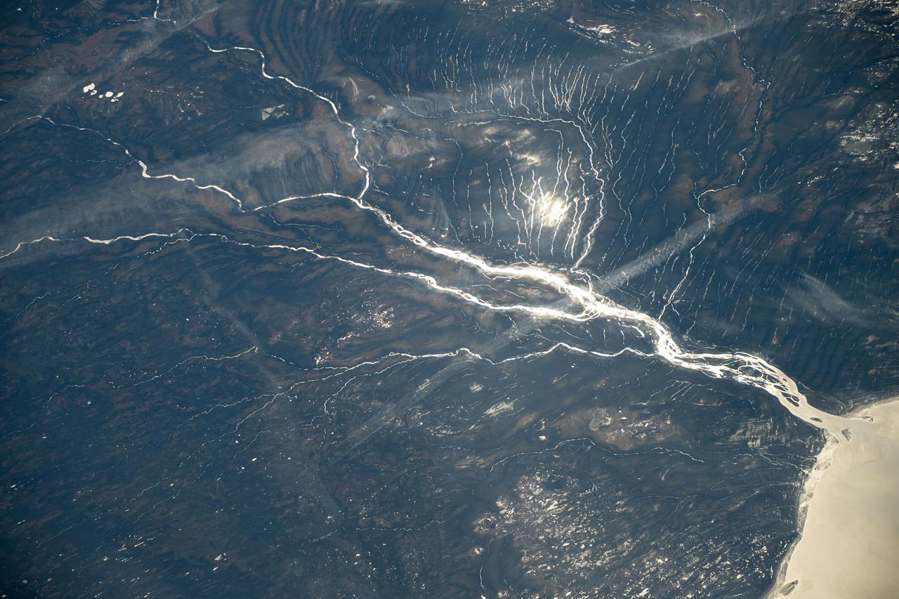 iss071e144724 (May 30, 2024) --- A sun glint-lit Moose River flows into James Bay in Ontario, Canada, in this photograph from the International Space Station as it orbited 264 miles above North America.
