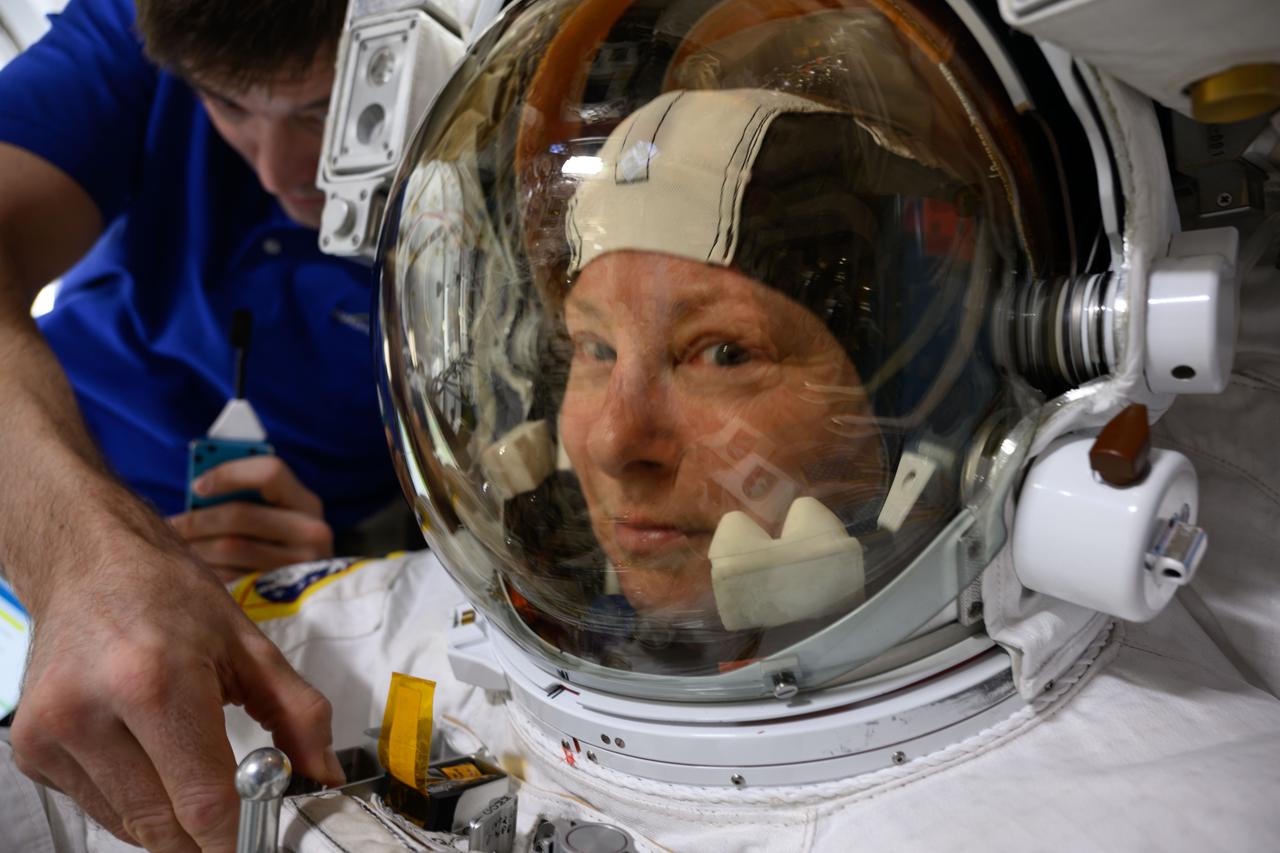 iss071e207747 (June 24, 2024) --- NASA astronaut and Expedition 71 Flight Engineer Tracy C. Dyson is pictured in her spacesuit prior to the start of a science and maintenance spacewalk that ended early on June 24, 2024, after her suit experienced a water leak in the service and cooling umbilical unit. Fellow astronaut and flight engineer Matthew Dominick is pictured assisting Dyson inside the International Space Station's airlock.