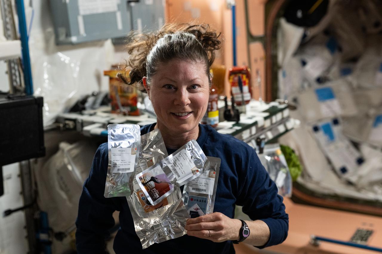 iss071e297201 (July 9, 2024) --- NASA astronaut and Expedition 71 Flight Engineer Tracy C. Dyson is pictured in the galley aboard the International Space Station's Unity module showing off food packets from JAXA (Japan Aerospace Exploration Agency).