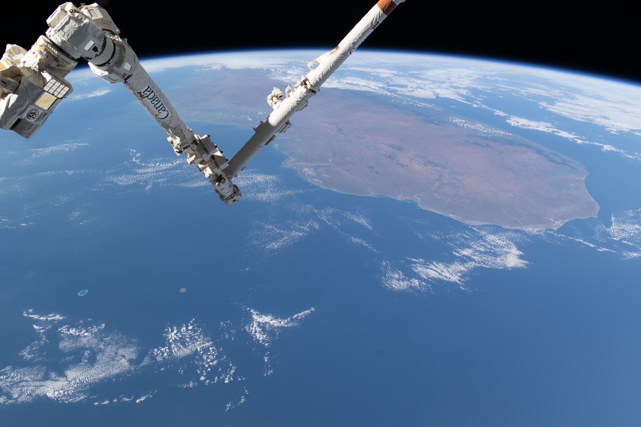 iss071e361950 (July 15, 2024) --- The International Space Station's 57.7-foot-long Canadarm2 robotic arm crosses the foreground as the orbital outpost soared 265 miles above the Mozambique Channel south of the African island nation of Madagascar.