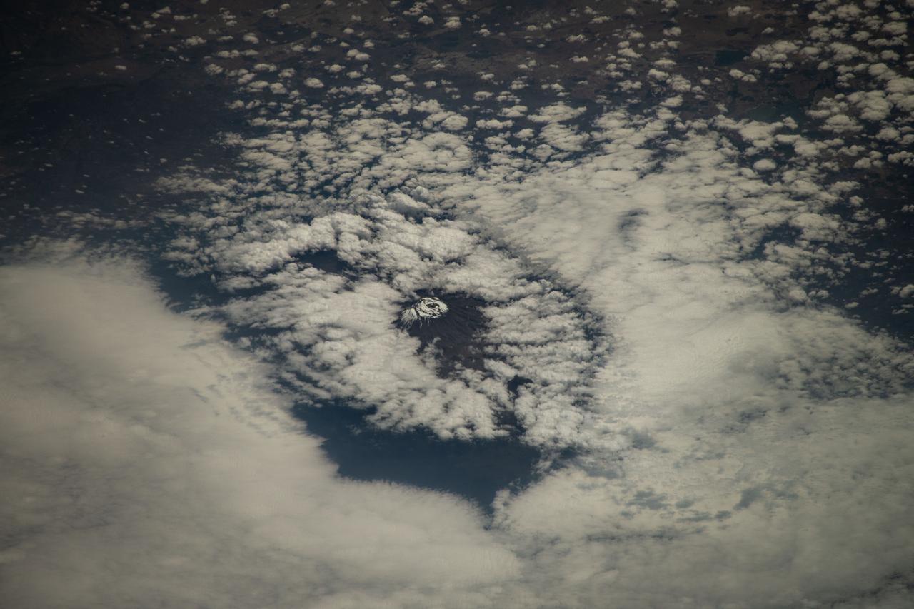 iss071e378517 (July 21, 2024) --- Mount Kilimanjaro, surrounded by clouds and the highest mountian in Africa, is pictured from the International Space Station as it orbited 261 miles above the Indian Ocean off the coast of Tanzania.