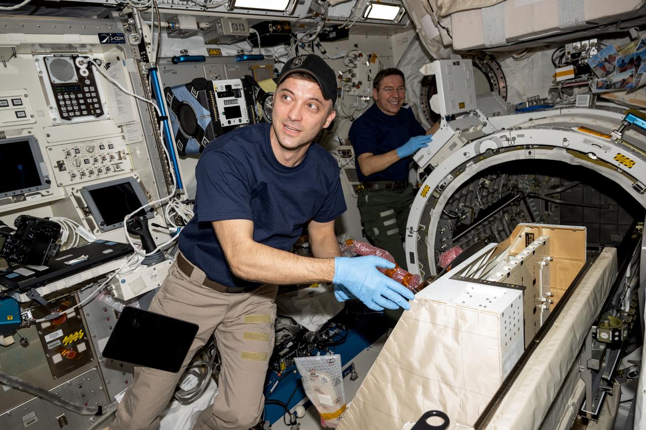 iss071e403564 (July 22, 2024) --- (From left) NASA astronauts Matthew Dominick and Mike Barratt, both Expedition 71 Flight Engineers, install the NanoRacks external platform inside the Kibo laboratory module's airlock. The platform from NanoRacks can host a variety of payloads placed outside the International Space Station and exposed to the external space environment for science experiments, technology demonstrations, and more.