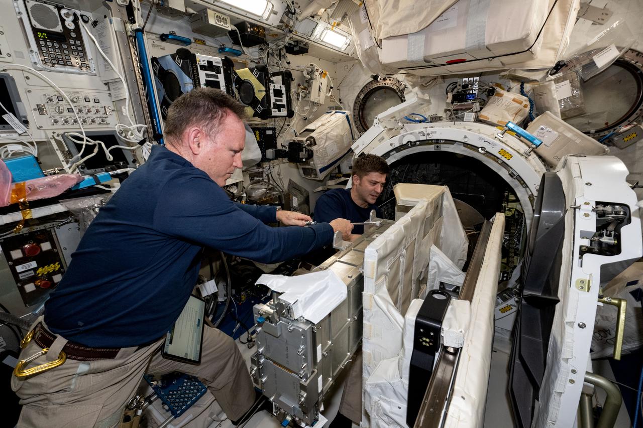 iss071e523320 (Aug. 21, 2024) --- NASA astronauts (from left) Butch Wilmore, Commander for Boeing's Crew Flight Test, and Matthew Dominick, Expedition 71 Flight Engineer, check CubeSat configurations inside the Small Satellite Orbital Deployer aboard the International Space Station's Kibo laboratory module.