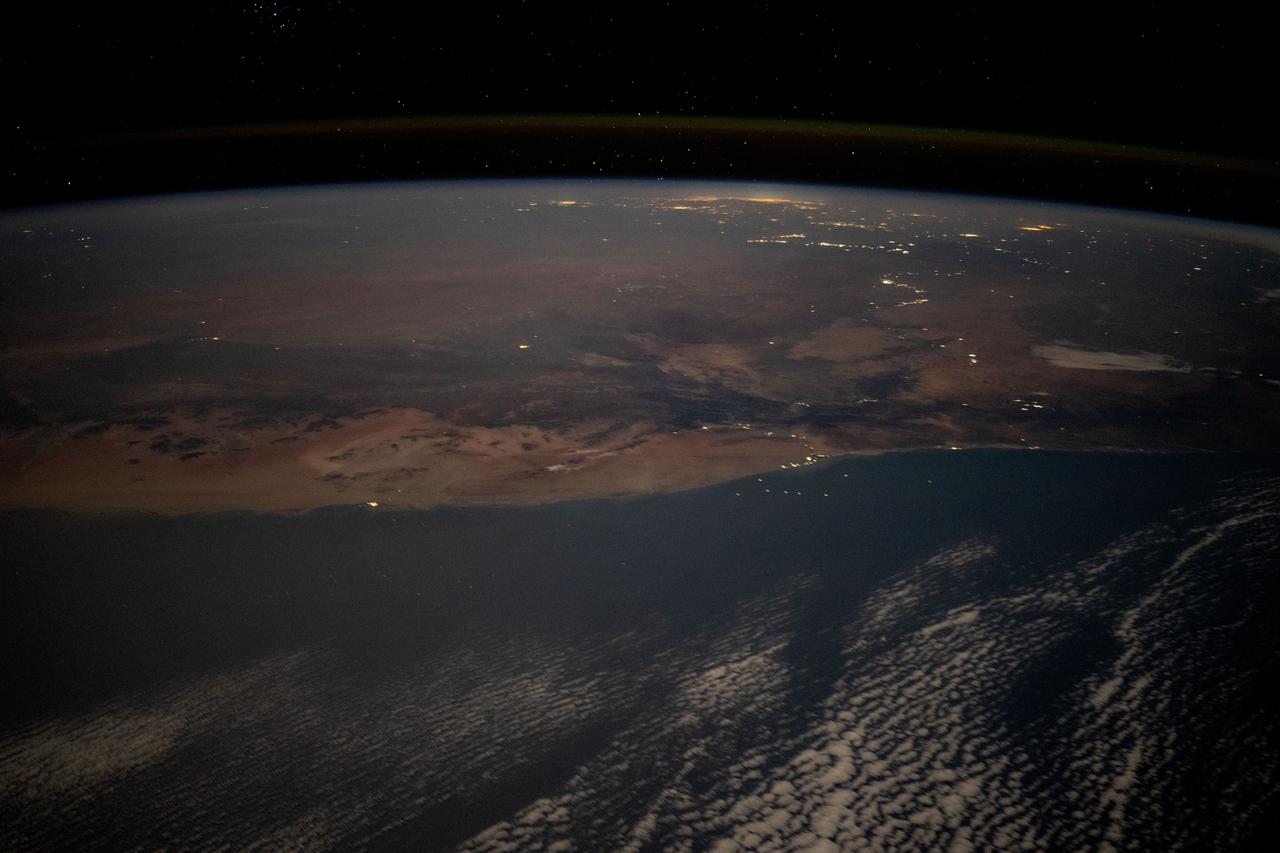 iss071e523401 (Aug. 21, 2024) --- The desert coast of Namibia and the city lights of Johannesburg, South Africa, and surrounding areas on Earth's horizon are pictured from the International Space Station as it soared 263 miles above the Atlantic Ocean in this nighttime photograph.