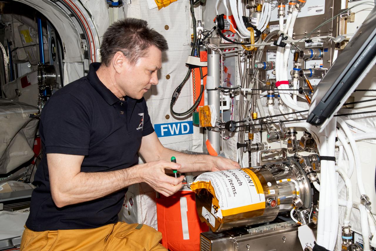 iss071e580240 (AUg. 29, 2024) --- Roscosmos cosmonaut and Expedition 71 Commander Oleg Kononenko swaps sample chambers inside the Electromagnetic Levitator (EML) located aboard the International Space Station's Columbus laboratory module. The EML is a physics research device that measures the thermophysical properties of liquid metallic alloys at high temperatures.
