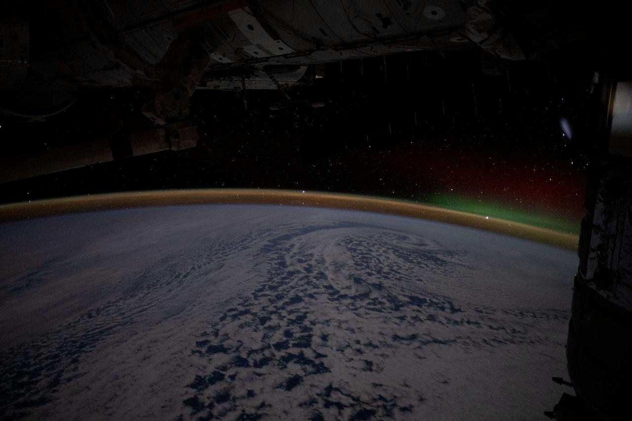 iss071e586401 (Aug. 13, 2024) --- A wispy aurora australis rises above Earth's airglow blanketing the horizon in this long-duration photograph from the International Space Station as it orbited 270 miles above the Pacific Ocean southeast of New Zealand.