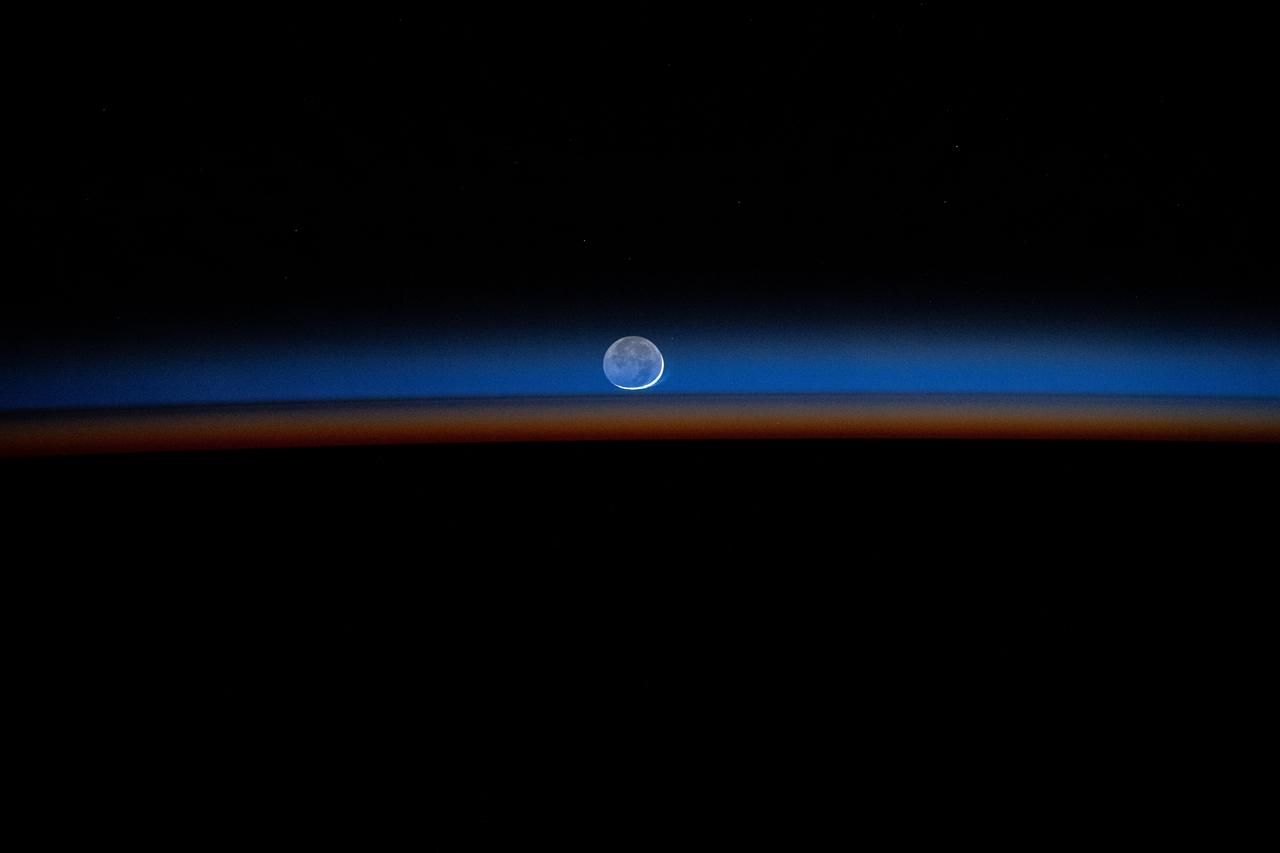 iss071e609065 (Sept. 4, 2024) --- The New Moon sets behind Earth's colorful, but dimming atmosphere in this long-duration photograph taken by NASA astronaut Matthew Dominick with a camera programmed for high sensitivity aboard the International Space Station.