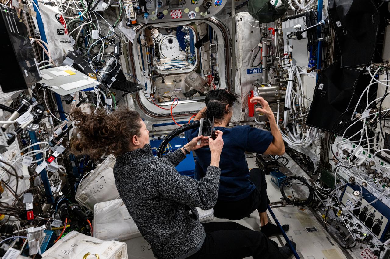 iss071e665837 (Sept. 15, 2024) --- NASA astronaut Tracy C. Dyson trims NASA astronaut Suni Williams hair aboard the International Space Station's Columbus laboratory module.