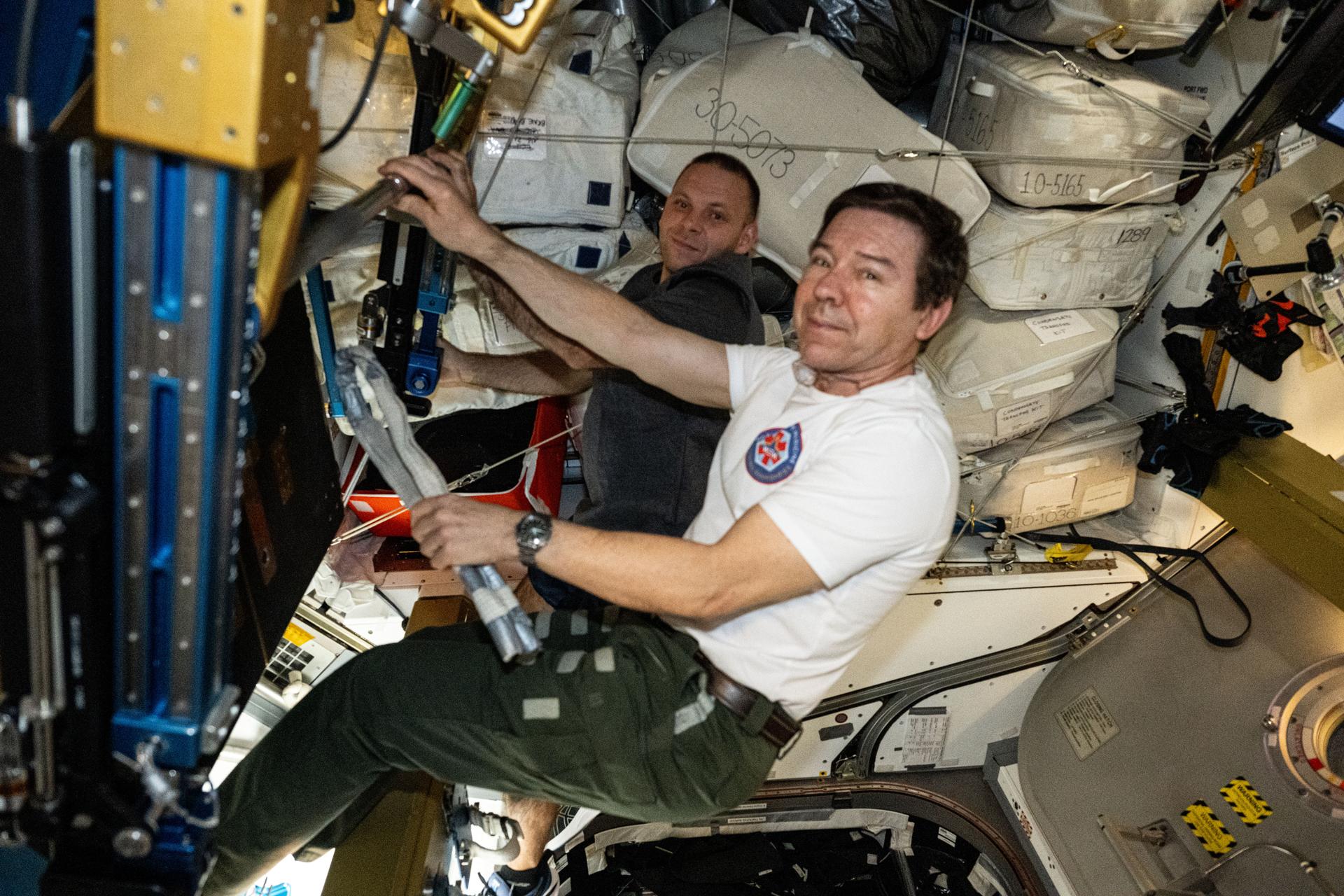 NASA astronaut Mike Barratt (foreground) and Roscosmos cosmonaut Ivan Vagner, both Expedition 71 Flght Engineers, examine the International Space Station's advanced resistive exercise device (ARED) located in the Tranquility module. The ARED mimics the inertial load of free weights on Earth helping crews maintain muscle strength and mass during long periods in the weightless environment of space.