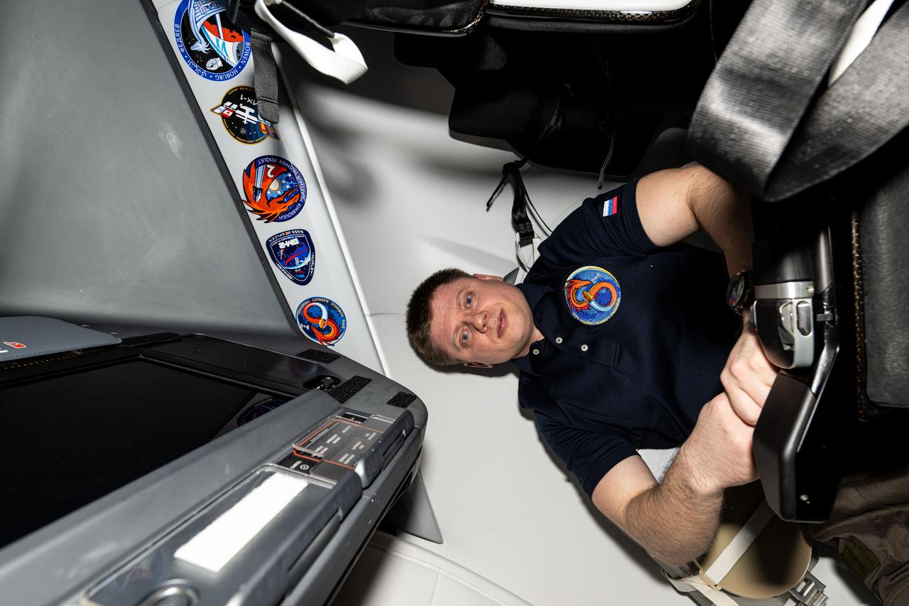iss072e005806 (Sept. 28, 2024) --- Roscosmos cosmonaut and Expedition 72 Flight Engineer Alexander Grebenkin poses for a portrait inside the SpaceX Dragon Endeavour spacecraft docked to the Harmony module's space-facing port on the International Space Station. Gorbunov appears next to his mission's insignia, SpaceX Crew-8, alongside the insignias of four other missions that have launched to space aboard Dragon Endeavour.