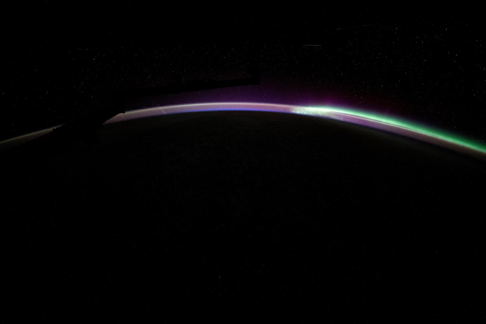The aurora australis blends with Earth's atmospheric glow blanketing the nighttime horizon in this photograph from the International Space Station as it orbited 271 miles above the Pacific Ocean off the coast of New Zealand.