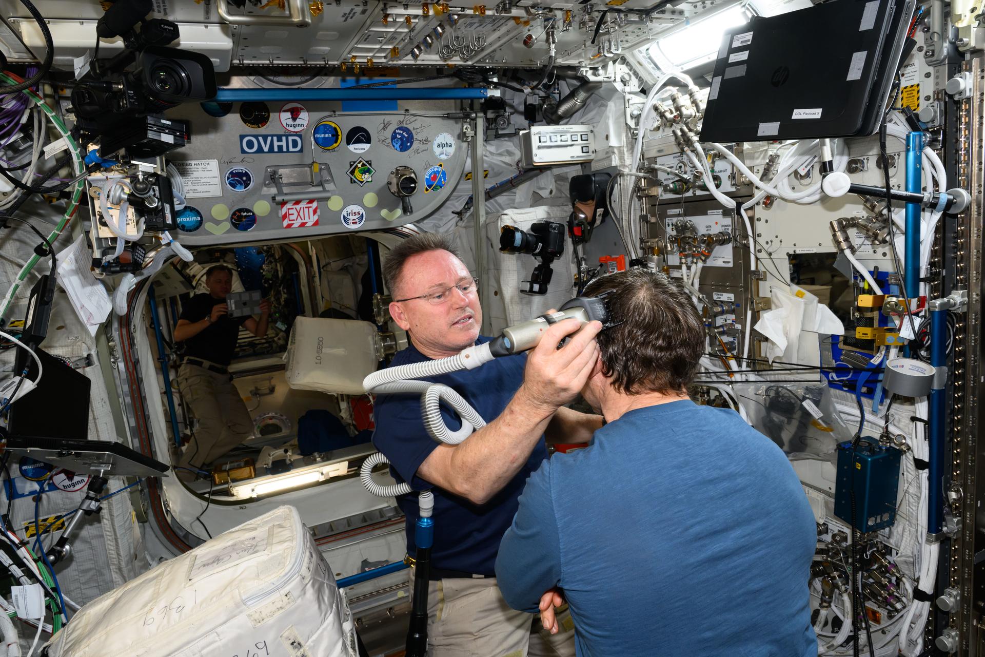 It's haircut day on the International Space Station. Expedition 72 Flight Engineer Butch Wilmore trims Expedition 72 Flight Engineer Mike Barratt's hair using an electric razor with a vacuum attached that collects the loose hair.