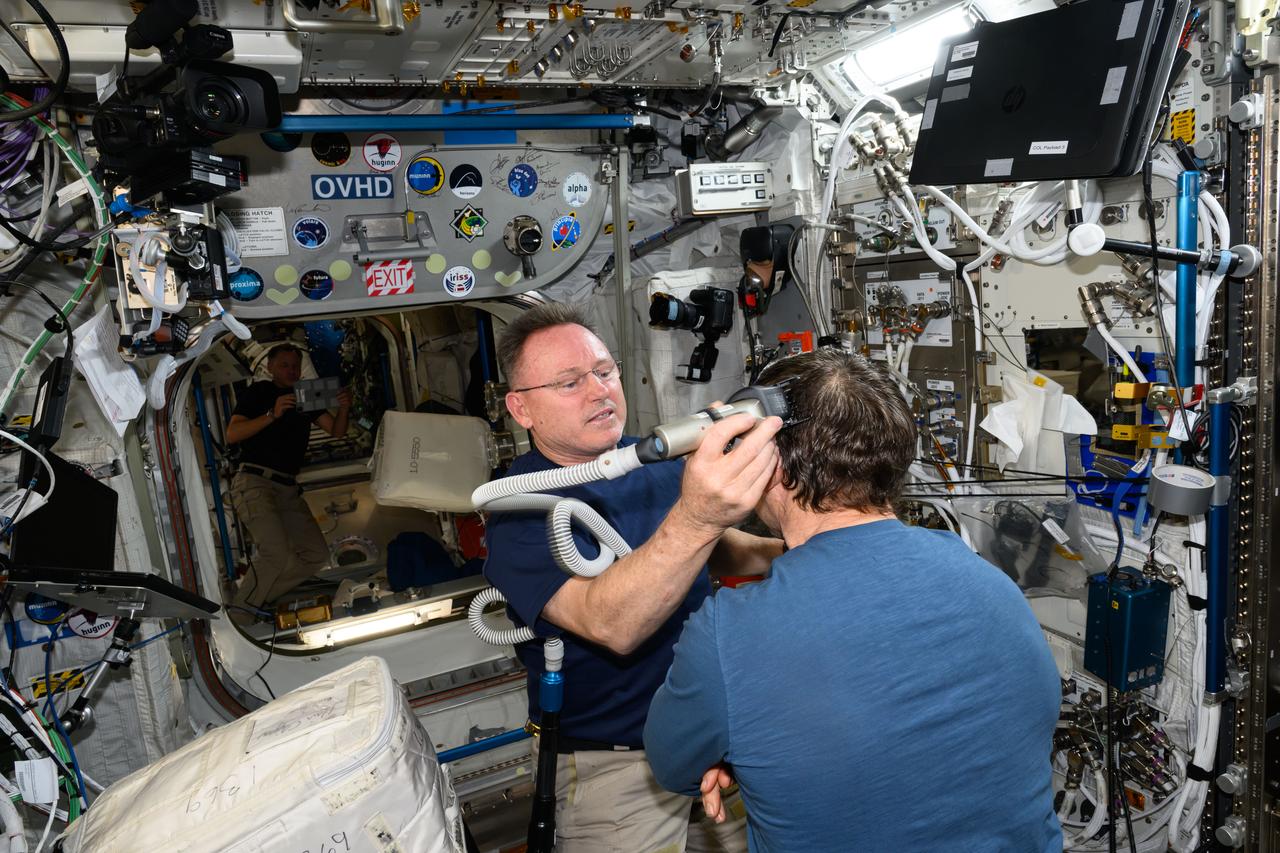 iss072e014279 (Oct. 6, 2024) --- It's haircut day on the International Space Station. Expedition 72 Flight Engineer Butch Wilmore trims Expedition 72 Flight Engineer Mike Barratt's hair using an electric razor with a vacuum attached that collects the loose hair.