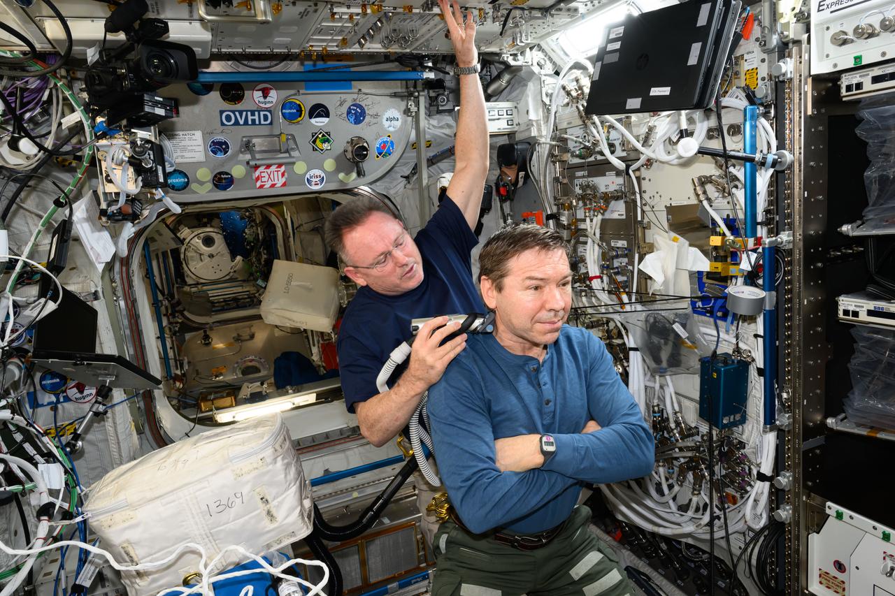 iss072e014281 (Oct. 6, 2024) --- It's haircut day on the International Space Station. Expedition 72 Flight Engineer Butch Wilmore trims Expedition 72 Flight Engineer Mike Barratt's hair using an electric razor with a vacuum attached that collects the loose hair.