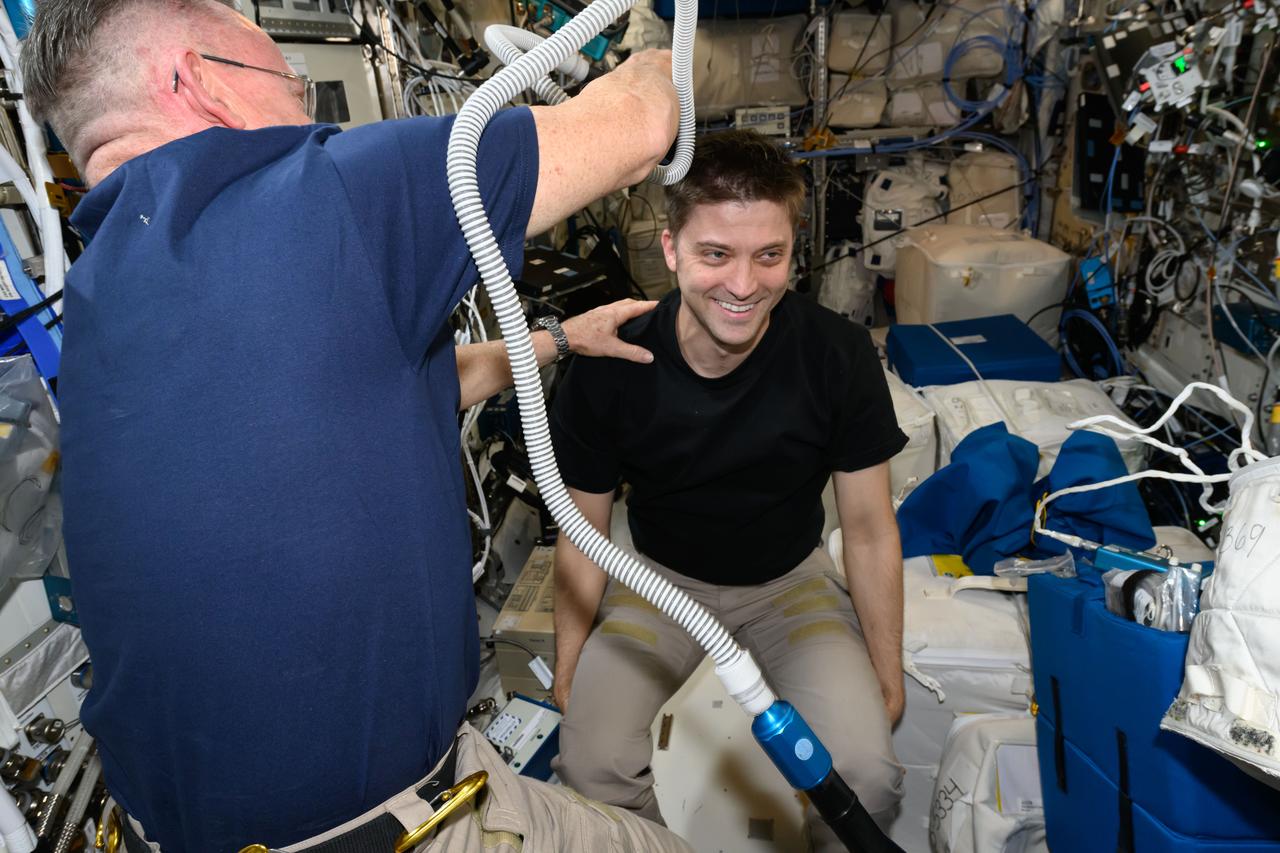 iss072e014366 (Oct. 6, 2024) --- It's haircut day on the International Space Station. Expedition 72 Flight Engineer Butch Wilmore trims Expedition 72 Flight Engineer Matthew Dominck's hair using an electric razor with a vacuum attached that collects the loose hair.