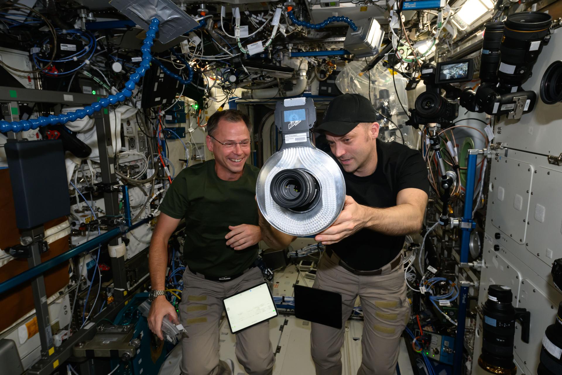 739C3872.NASA astronauts (from left) Nick Hague and Matthew Dominick, both Expedition 72 Flight Engineers, check out a camera and its lighting hardware aboard the International Space Station.