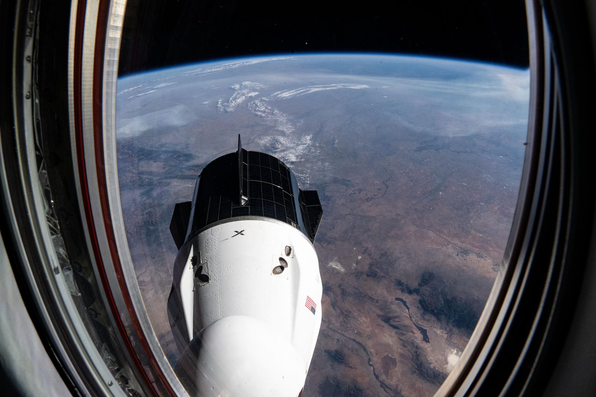 The SpaceX Dragon Freedom spacecraft is pictured from a window on the Dragon Endeavour spacecraft in a photograph taken by NASA astronaut and Expedition 72 Flght Engineer Nick Hague. 258 miles below the International Space Station is the Sunflower State of Kansas.