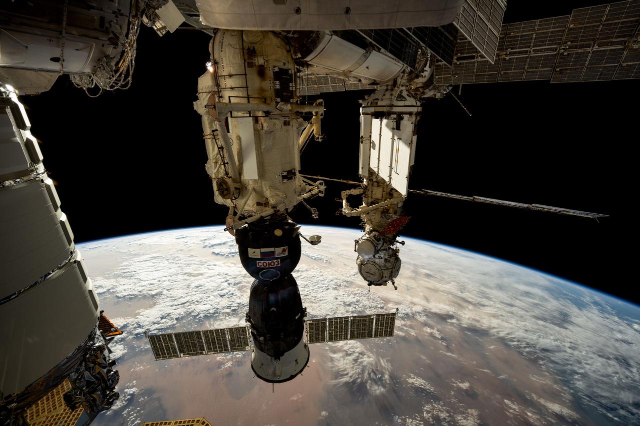 iss072e032692 (Oct. 8, 2024) --- The Soyuz MS-26 crew ship (foreground) from Roscosmos is pictured docked to the International Space Station's Rassvet module. In the background, the Prichal docking module is pictured attached to the Nauka science module with the European robotic arm connected to it. 261 miles below the orbiting laboratory is the African nation of Libya.
